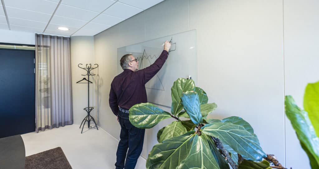Michael Bisling tegner en isbjergsmodel på en glasskrivetavle i sin klinik.